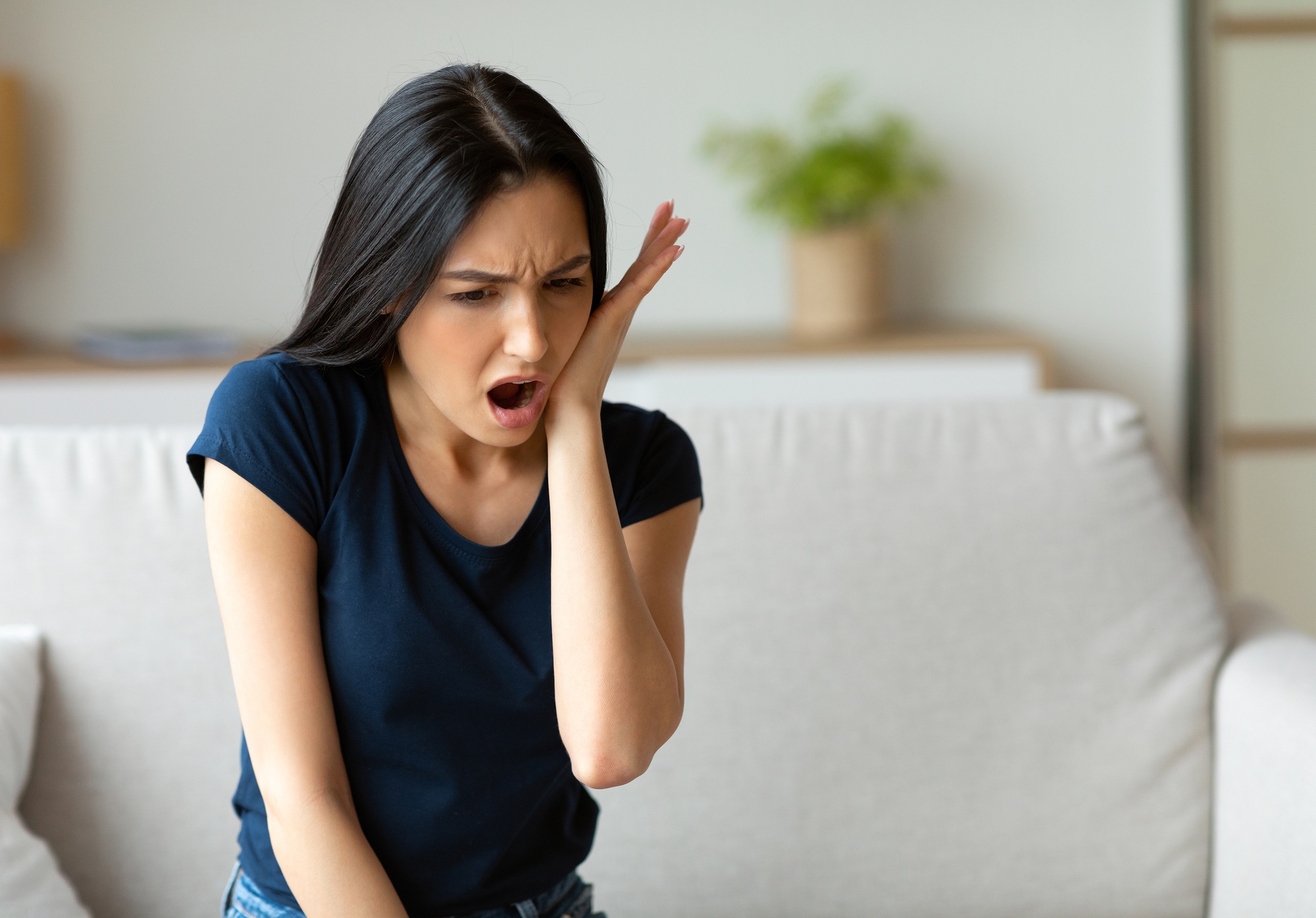 Girl Suffering From Tooth Pain Touching Cheek Sitting At Home